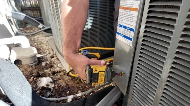 Technician performing maintenance on a residential outdoor condenser