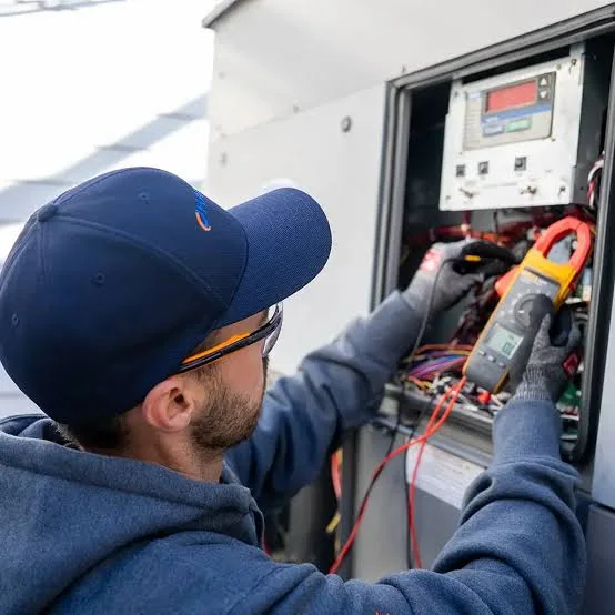 Technician testing an HVAC electrical control panel