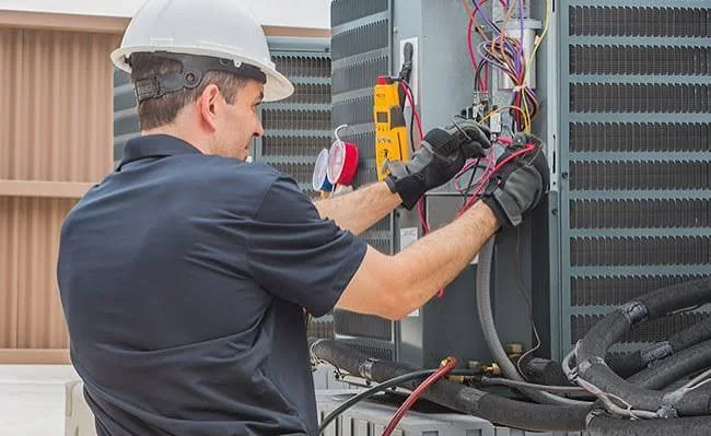 HVAC technician testing electrical components in an outdoor air conditioning unit