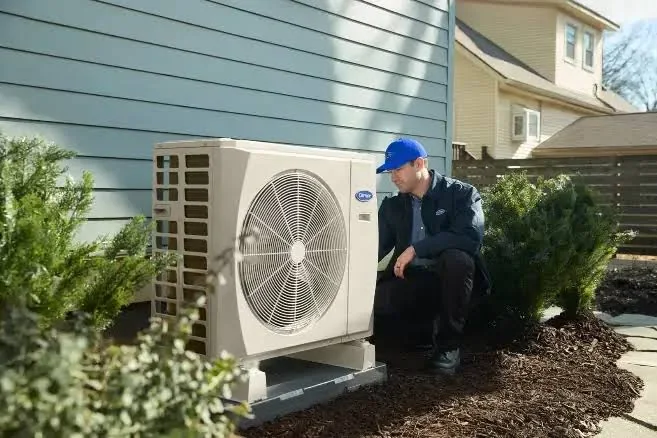 Technician inspecting a residential outdoor heat pump