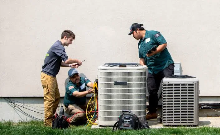 Team of HVAC technicians servicing residential outdoor condenser units